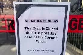 a small paper sign on a glass door stating "attention members. the gym is closed due to a possible case of the corona virus"